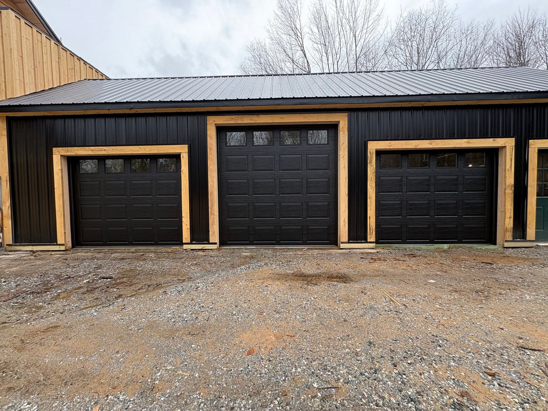 Modern black garage doors with gold trim on a metal building
