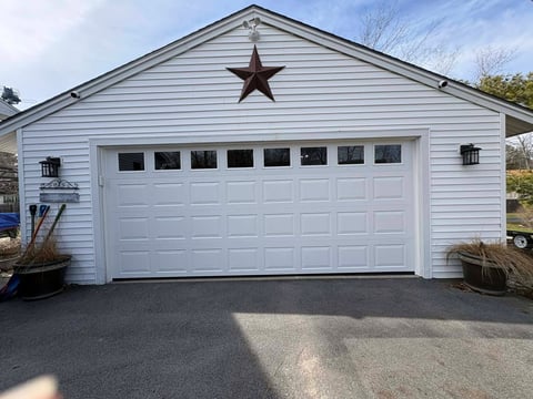 White garage with two-car door, decorative star above, and metal lanterns on either side